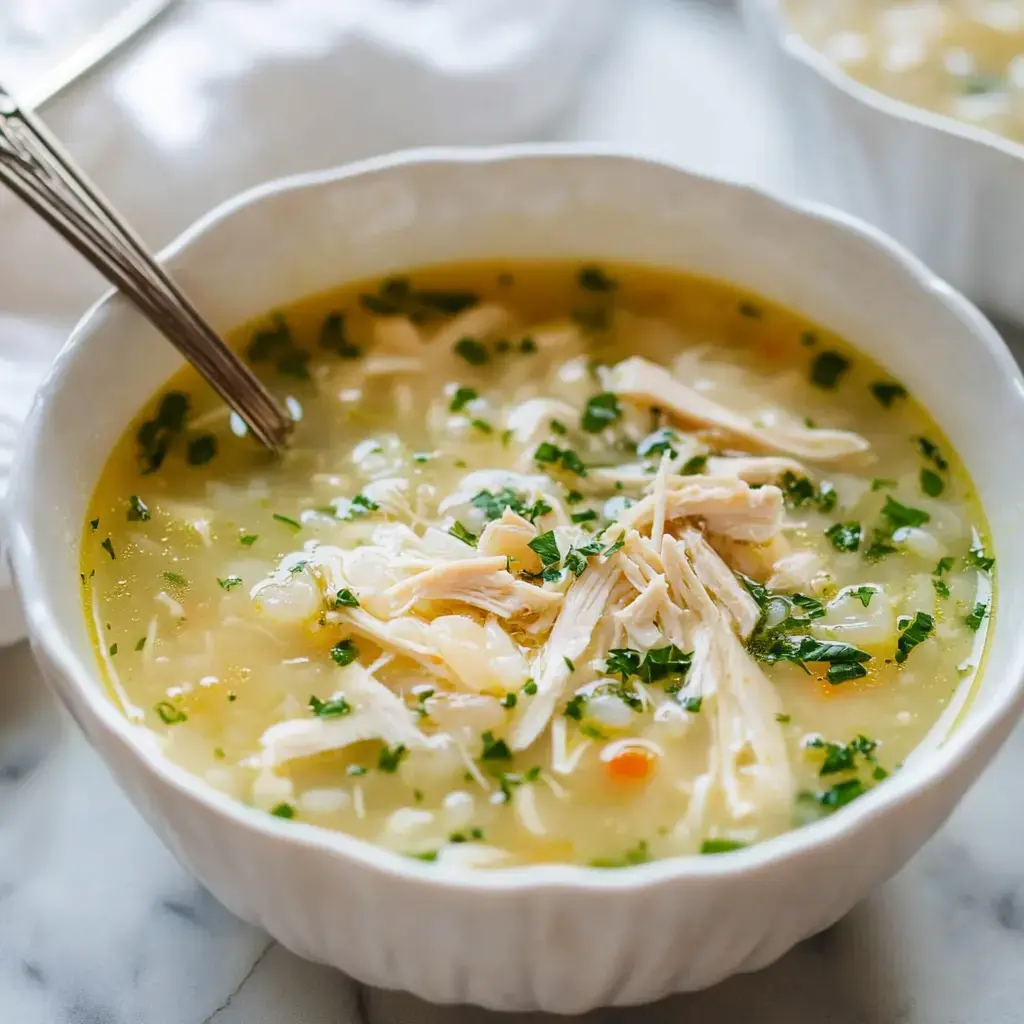 A bowl of soup made with chicken and topped with parsley.
