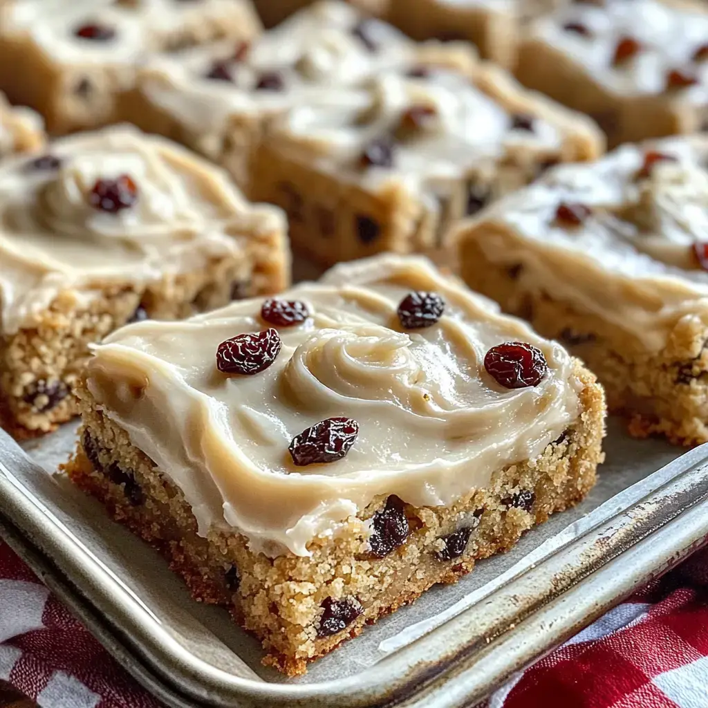 Close-up of frosted dessert squares with raisins on top.