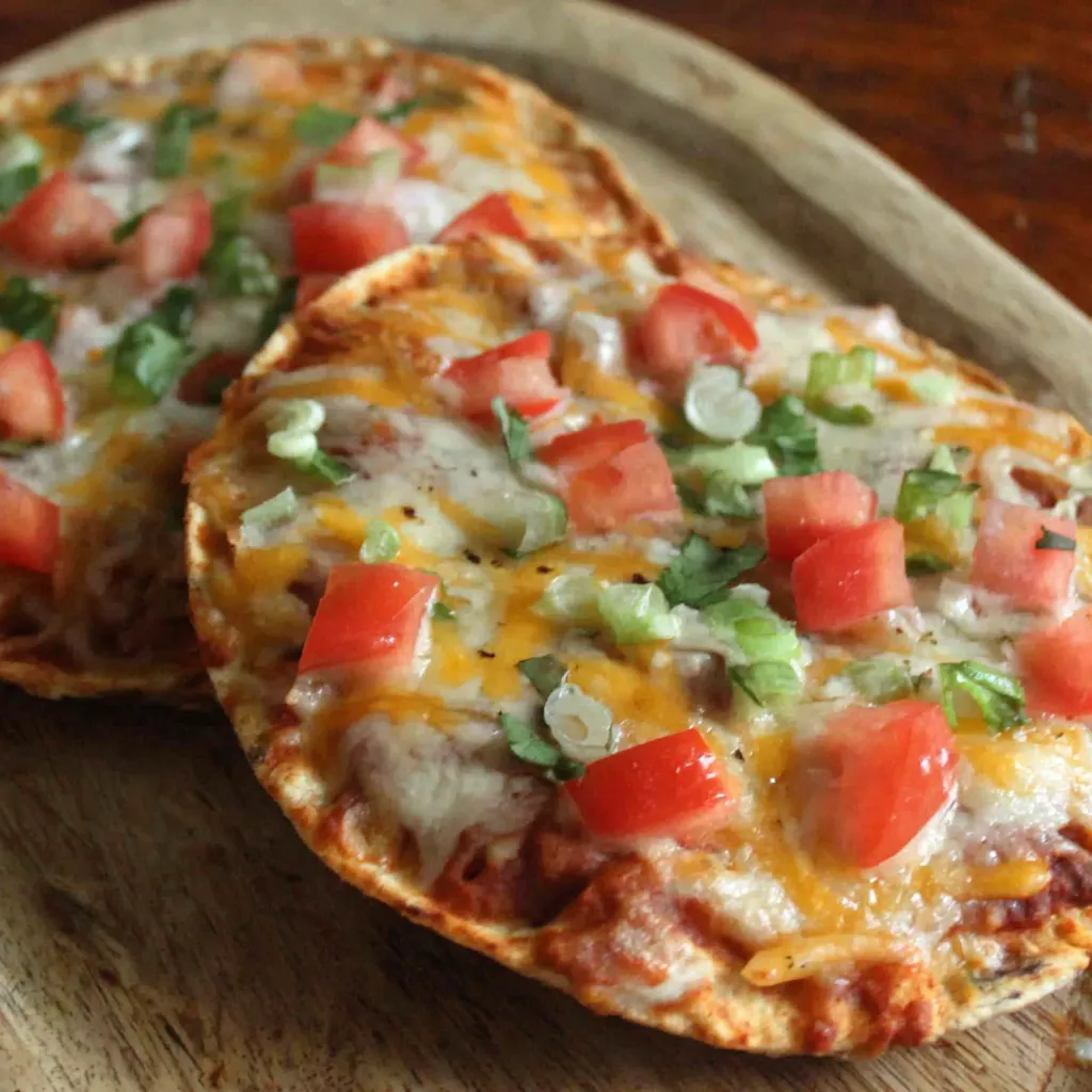 Two Mexican pizzas with cheese and tomatoes.
